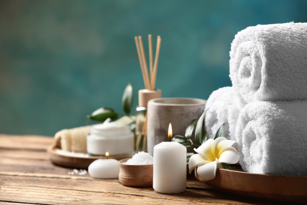 Spa still life with rolled towels, candles and a plumeria flower